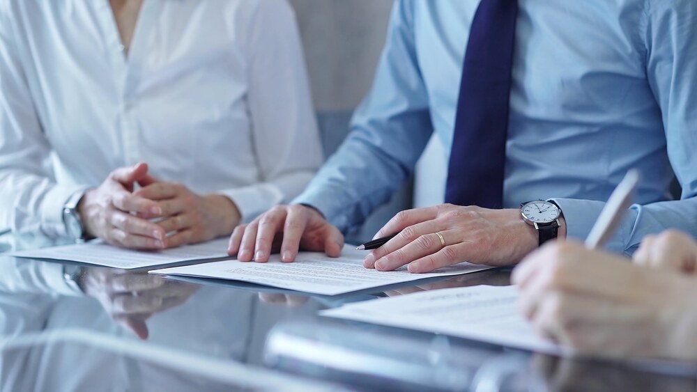 Business people reviewing contract documents with a pen at a glossy meeting table