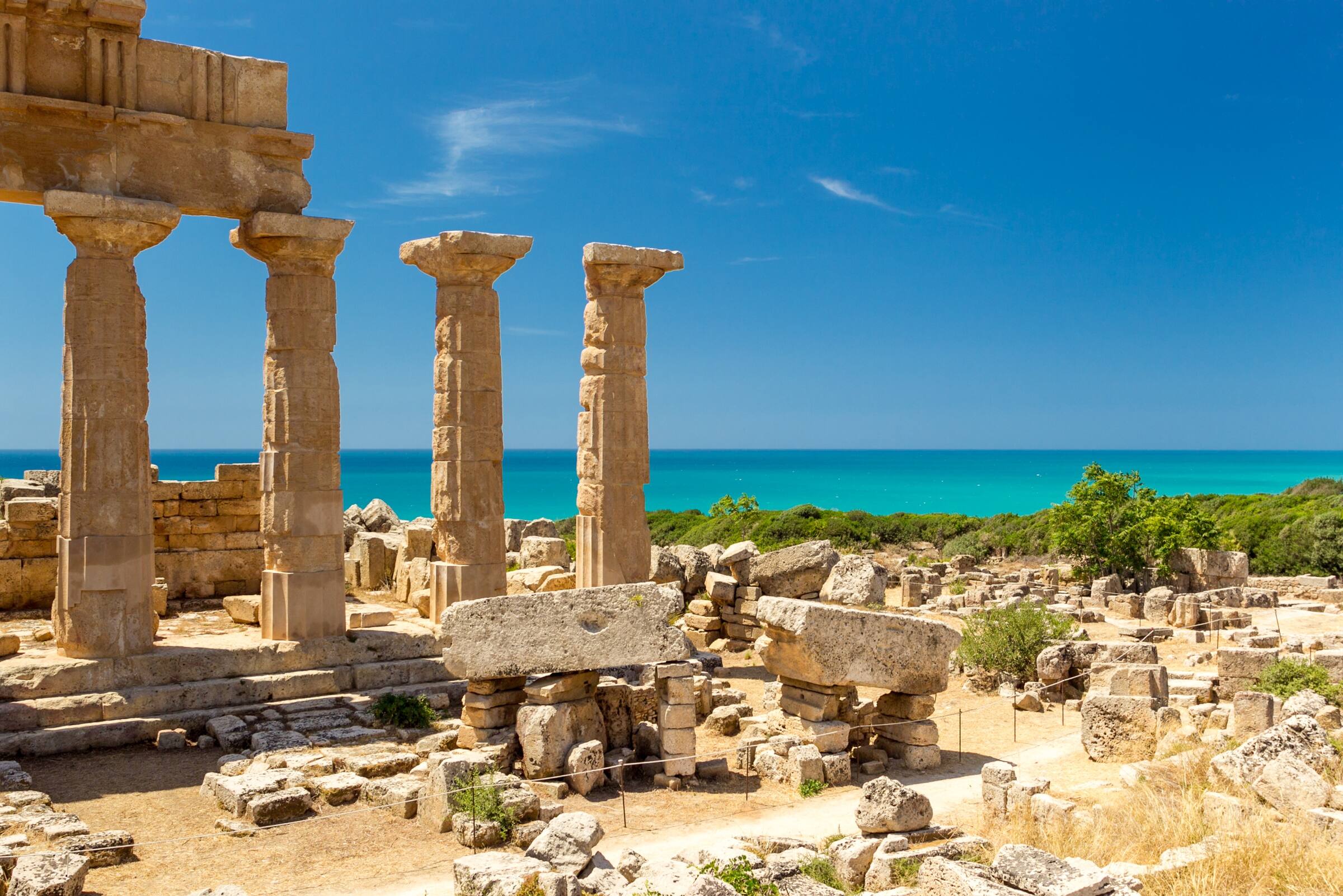 Doric columns of Temple C at Selinunte with ancient ruins and turquoise Sicilian sea